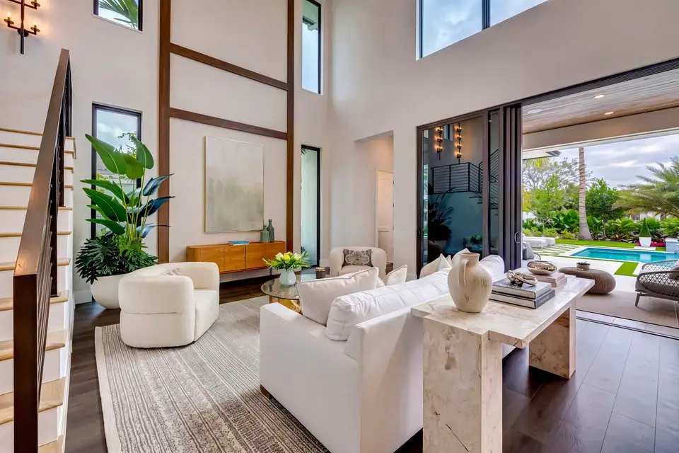 HDR photo of a double-height living room opening onto a pool through sliding glass doors